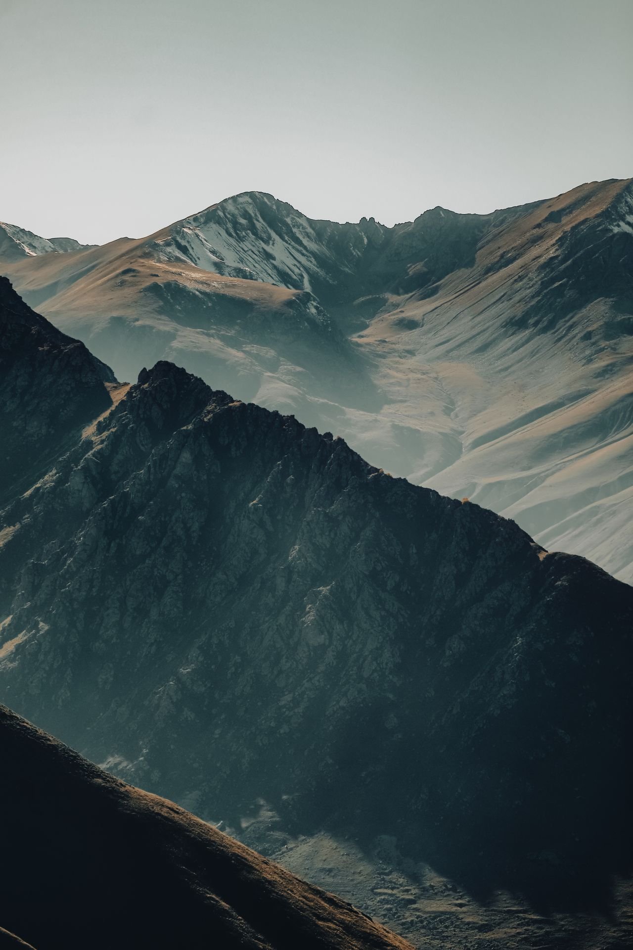 Captivating view of a rugged mountain range basking in early morning light, creating dramatic shadows.